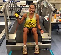 Susi Chan sitting on treeadmill holding up a bottle of champagne after breaking the world treadmill record in 2016
