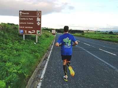 Runner on road approaching sign to Penrith