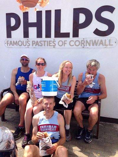 Five members of team sitting eating pasties in front of Philps Pasties sign