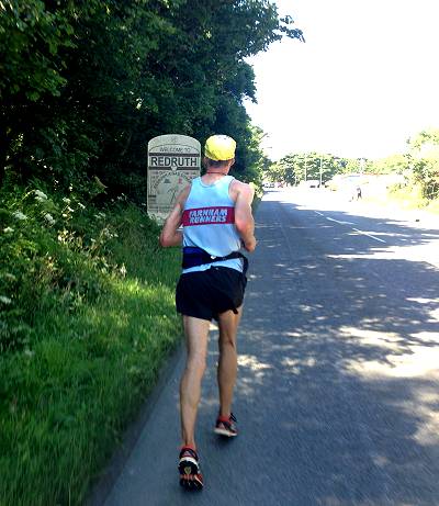 Runner on road approaching Redruth town sign