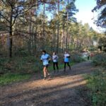 Running through the forest in the 2021 SXCL Bourne Woods race, Howard Inns heads Kay Copeland and Simon Dobinson