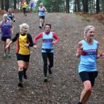 Terry Steadman, Kay Copeland and Jane Barry running down a steep downhillin the 2022-23 SXCL Bourne Woods cross-country in Farnham