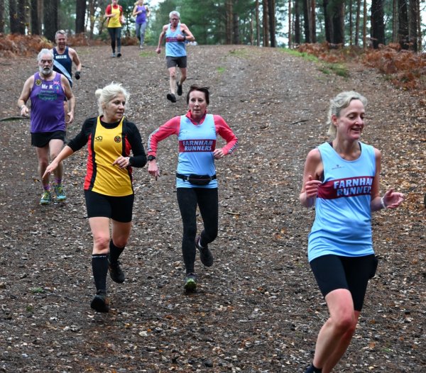 Terry Steadman, Kay Copeland and Jane Barry running down a steep downhillin the 2022-23 SXCL Bourne Woods cross-country in Farnham