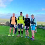 Justin Clarke, Ivan Chunnett, Chris Raby and Louise Granell posing near the finish of the the 2022 Gower Runs