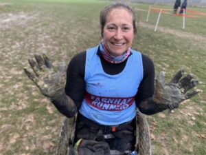 Rachel Morris in her wheelchair showing her muddy gloved hands after finishing the 2022 SXCL Lord Wandsworth College cross-country race