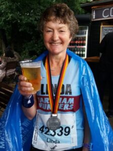 Linda Tyler after the 2017 Berlin Marathon with her medal and holding a beer