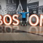 Linda Tyler posing against a Boston sign after the 2019 Boston Marathon