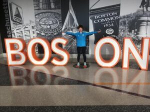 Linda Tyler posing against a Boston sign after the 2019 Boston Marathon