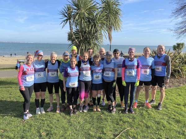 Group of Farnham Runners on what looks like a tropical island standing in front of palm trees before the start of 2023 Ryde 10