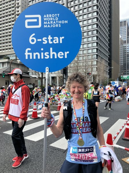 Linda Tyler holding a sign for having completed the World Marathon Majors after the 2023 Tokyo Marathon