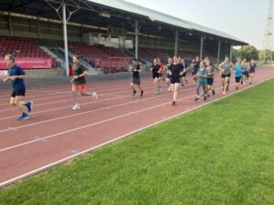 Participants running on the Aldershot athletics track duing a Farnham Runners Monday night training session