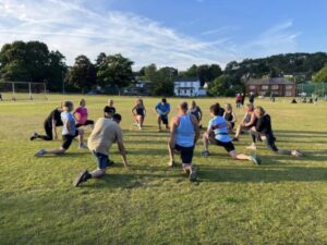 Attendees and their coaches stretching on the Bourne Green after a 2024 Get Me started session