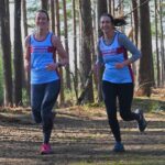 Lizzie Collins and Meg Grocott running the the woods at the 2024-25 SXCL Bourne Green cross-country