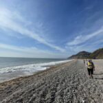 Competitors running along a gravel beach during the 2025 Grizzly race in Devon