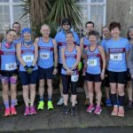 Farnham Runners group pose in front of a palm tree before the 2025 HRRL Ryde 10