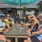 Group of Farnham Runners enjoying refreshments sitting in a pub courtyard after the 2025 Alton 10 race