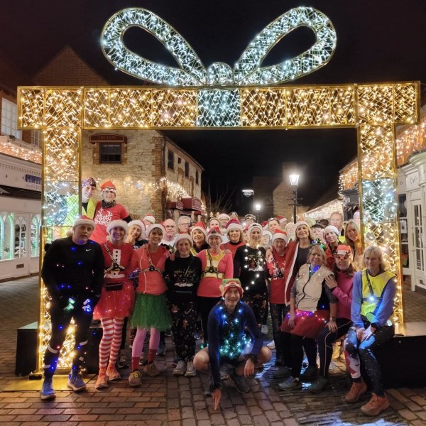 Farnham Runners group at the illuminated Christmas Arch in the Lion and Lamb Yard in Farnham during the 2025 Mince Pie run