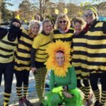 Six runners dressed as bees around Georgie Abrook dressed as a sunflower at the 2025 Club Handicap race