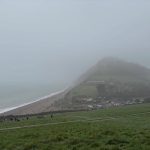 Misty coastal scene showing runners in the distant near running down a steep hill at the 2026 Grizzly race