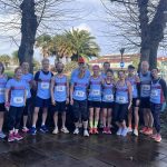 Farnham Runners men and ladies team posing in front of a palm tree in the sunshine before the HRRL 2026 Ryde 10