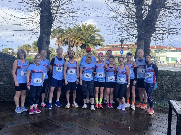 Farnham Runners men and ladies team posing in front of a palm tree in the sunshine before the HRRL 2026 Ryde 10